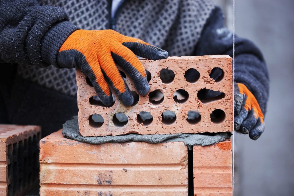 Gloved construction worker handling a brick